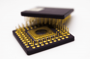 Two microprocessors with gold plated pins on a white background